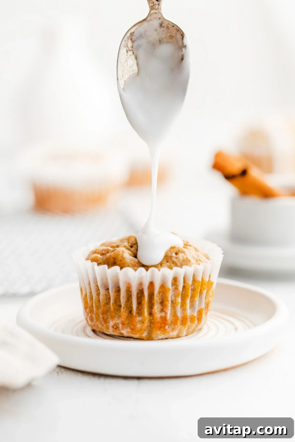 Close-up of a glazed carrot cake muffin, showing its moist texture and delicious frosting.