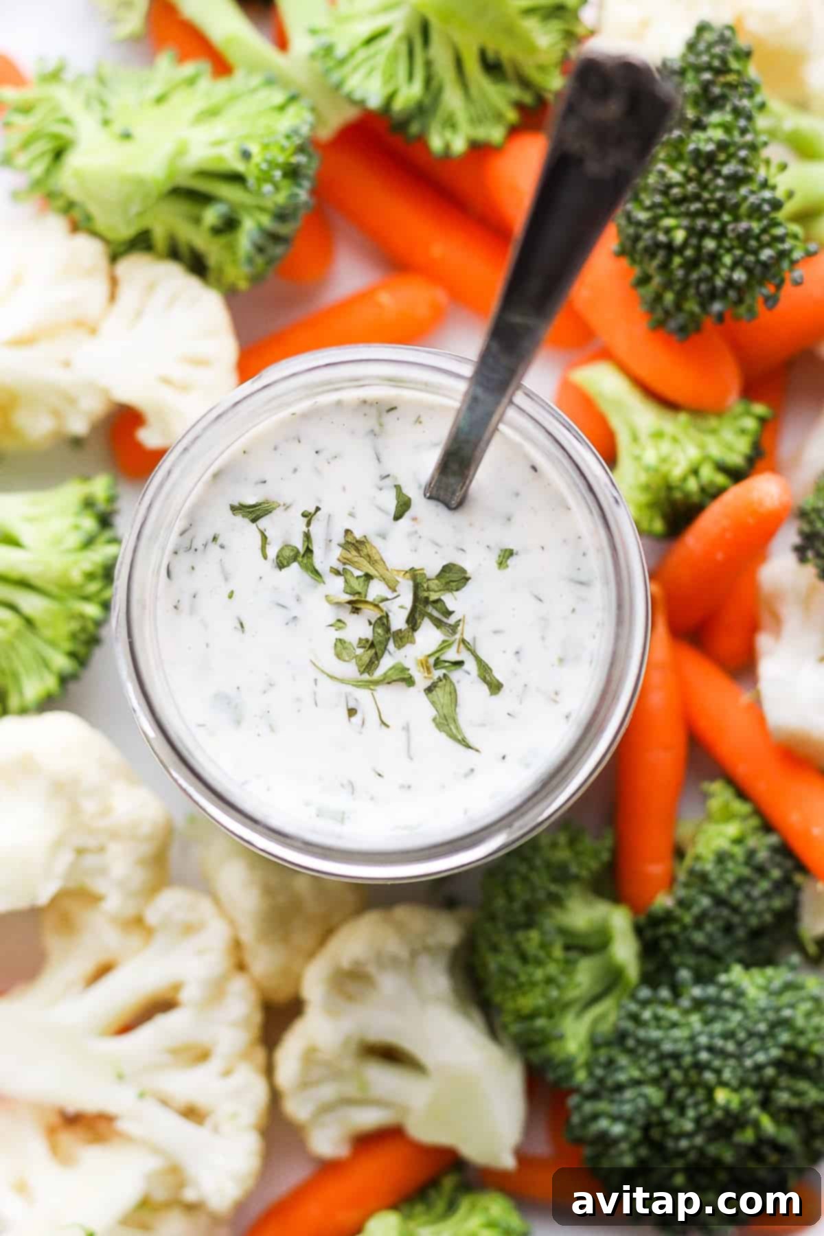 A glass jar filled with homemade ranch dressing, garnished with fresh herbs, ready for storage.