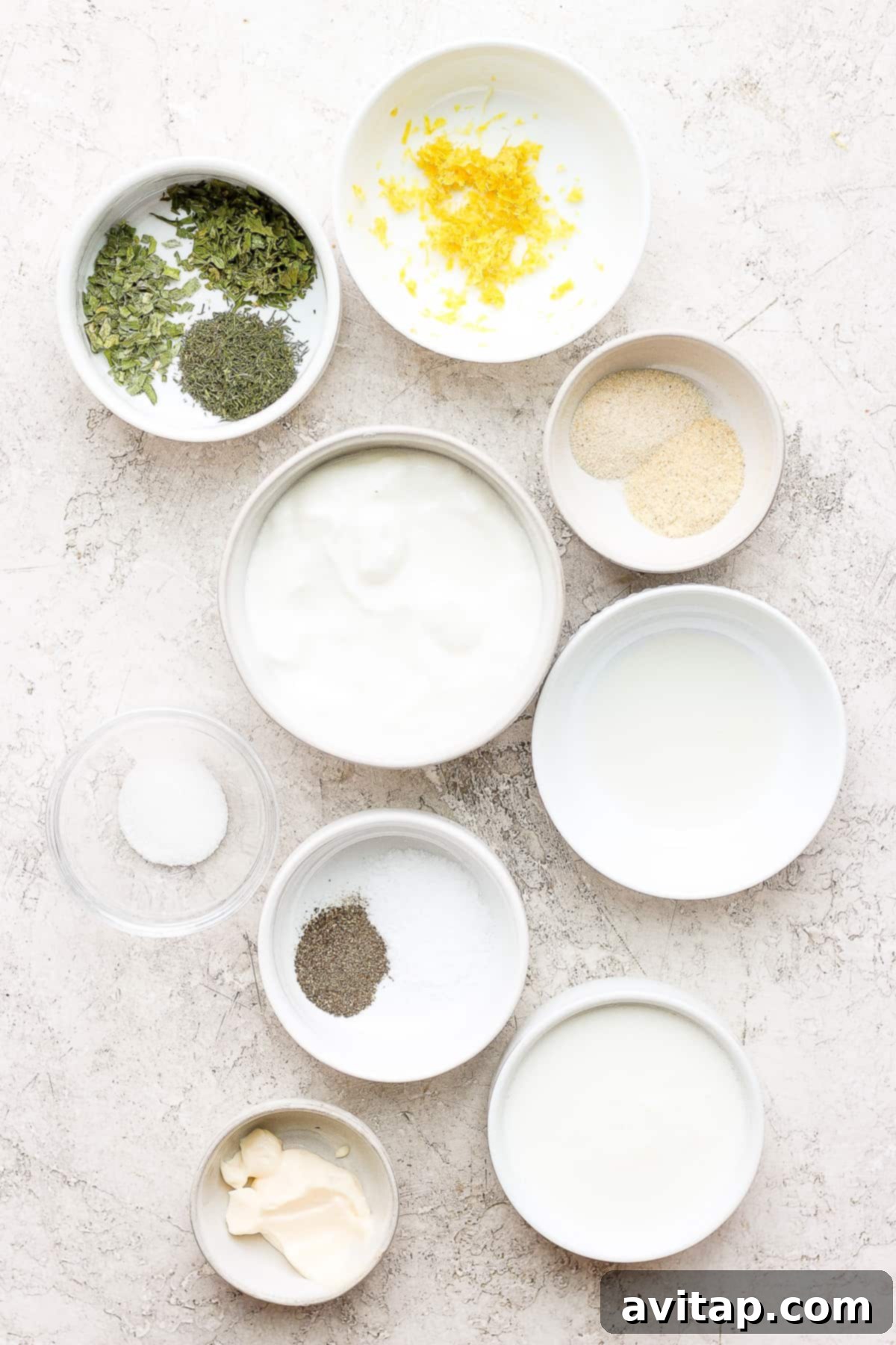 Assortment of fresh ingredients for homemade ranch dressing laid out on a kitchen countertop.