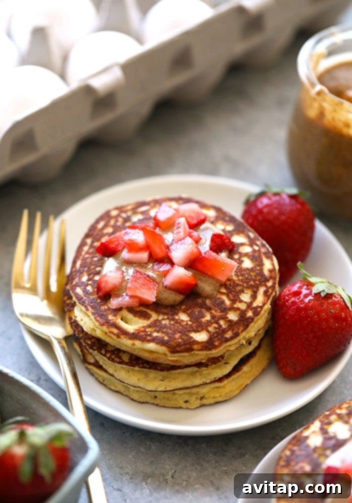 Stack of golden brown almond flour pancakes drizzled with syrup and topped with fresh berries.