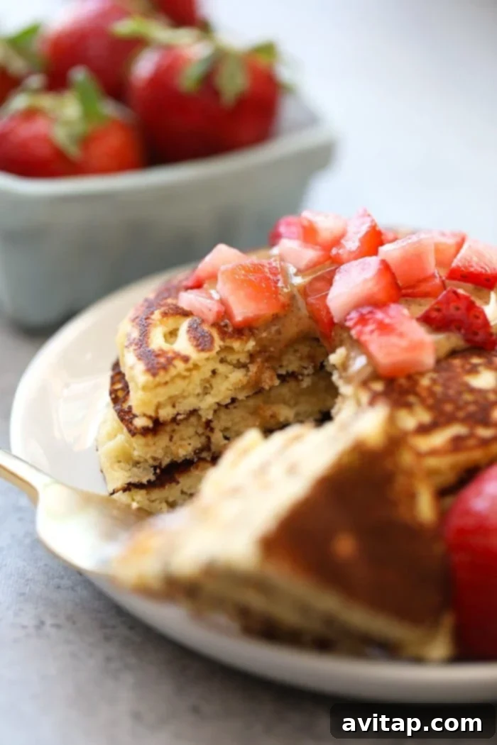 Close-up of almond flour pancakes beautifully arranged with fresh strawberry slices on top.