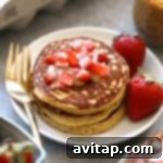 Almond flour pancakes topped with strawberries and peanut butter.