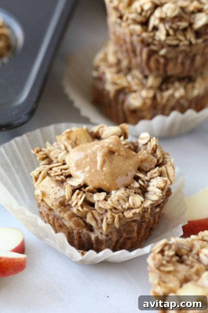 Individual baked apple oatmeal cups, one topped with peanut butter, showcasing a healthy and easy breakfast option.