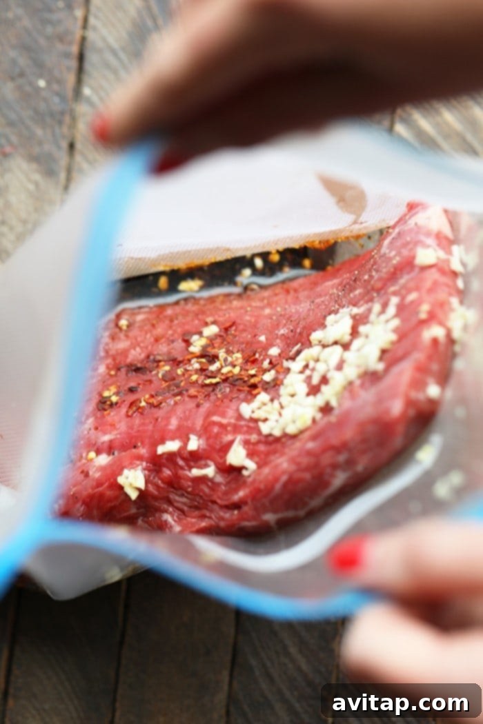 A close-up of thinly sliced Mongolian Sous Vide Flank Steak, revealing its juicy, pink interior, arranged neatly with a vibrant sauce and a sprinkle of sesame seeds, ready to be served.