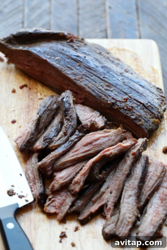 A perfectly seared flank steak resting on a cutting board, after being cooked sous vide, with a beautiful golden-brown crust and ready for slicing, surrounded by the finished Mongolian sauce.