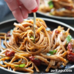 Mediterranean Sun-Dried Tomato Basil Pasta 2 A person holding a fork on a plate of Sun Dried Tomato Basil Pasta.