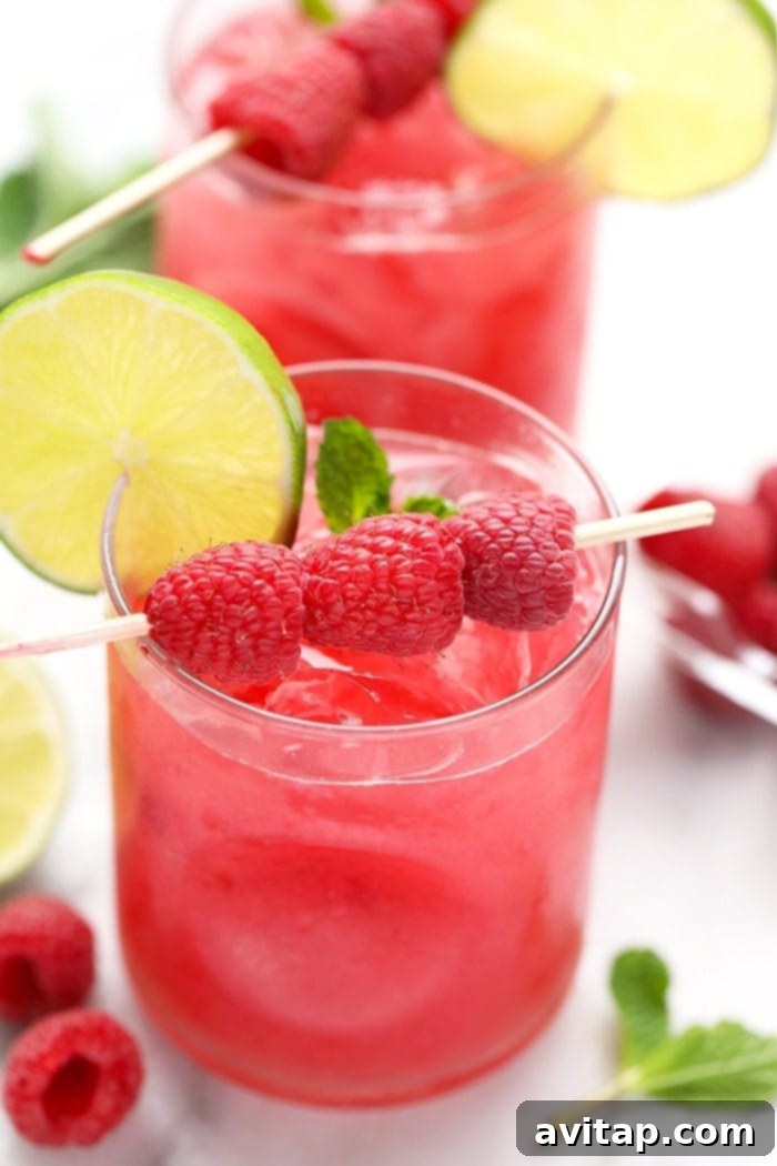 A refreshing glass of Ginger Raspberry Mojito with ice, mint, and lime garnish.