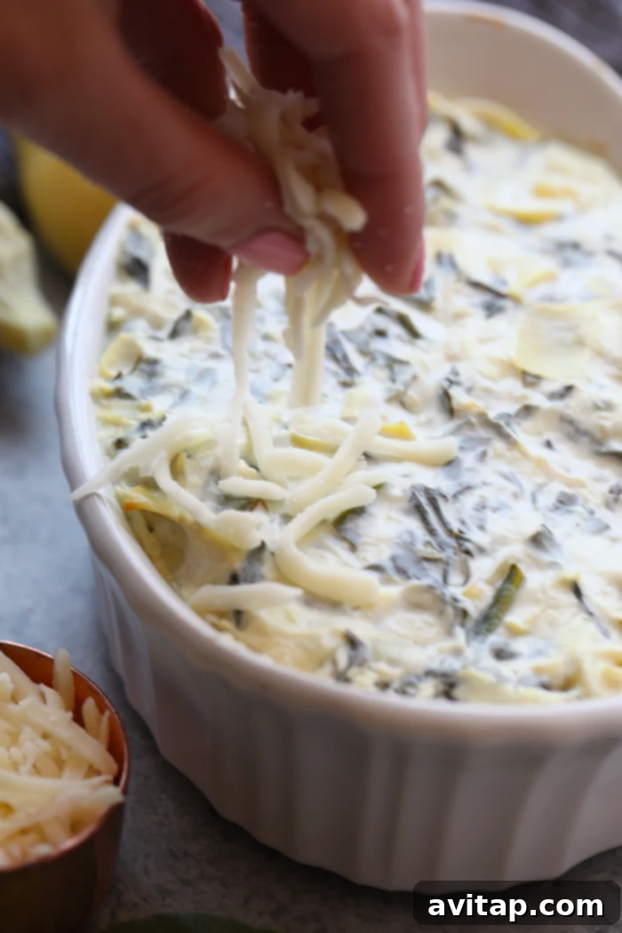 Enjoy this AMAZING lightened-up, restaurant-style Healthy Spinach and Artichoke Dip for a nutrition-packed snack or appetizer all year round. This spinach and artichoke dip will quickly become a crowd-pleasing recipe you'll make again and again. Uncooked spinach artichoke dip mixture spread evenly in a baking dish, ready for the oven.