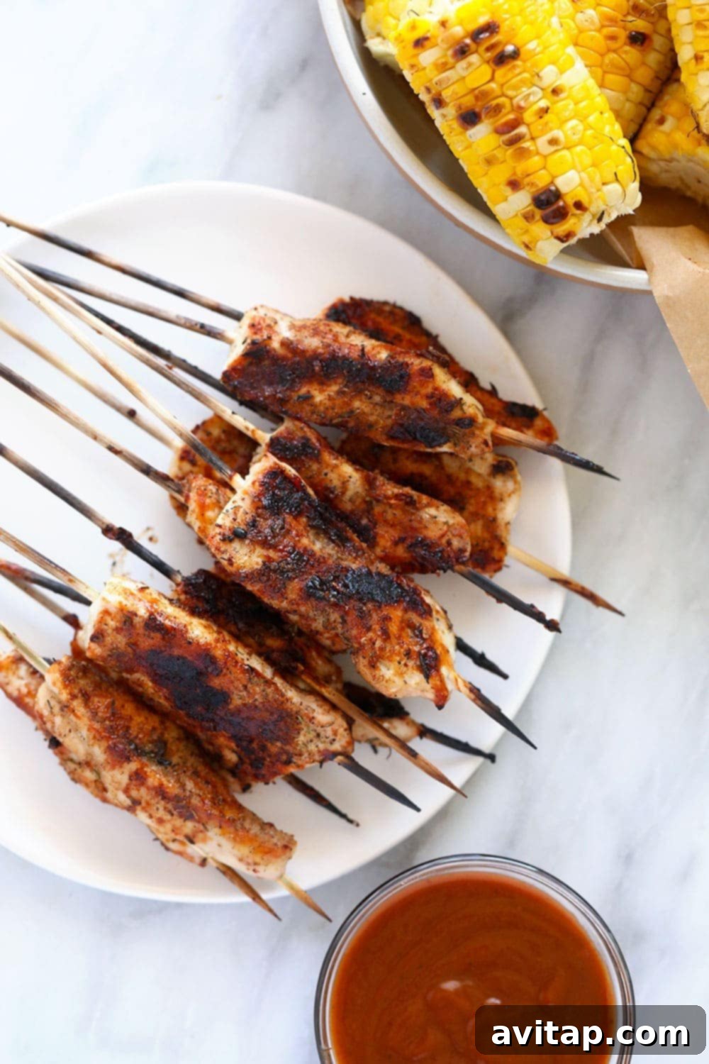 Perfectly grilled BBQ chicken skewers on a white plate, ready to be served.