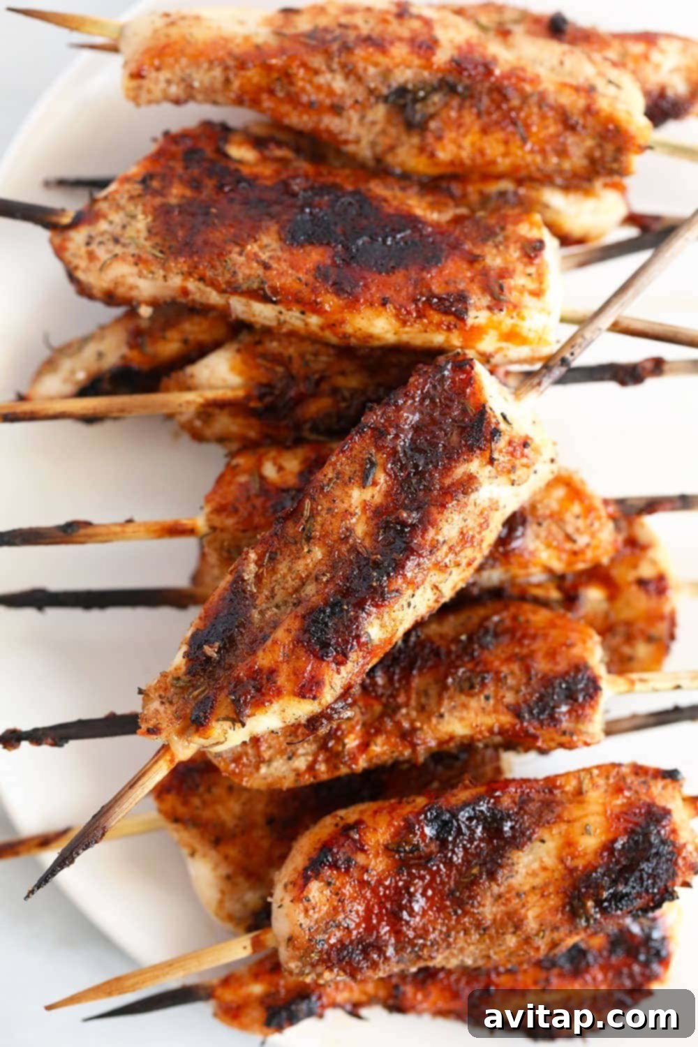 Freshly grilled BBQ chicken skewers served on a plate with grilled corn on the cob and a bowl of BBQ sauce, a perfect summer meal.