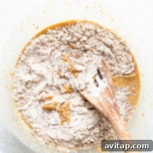 Dry flour mixture being gently folded into the wet ingredients for apple bread.