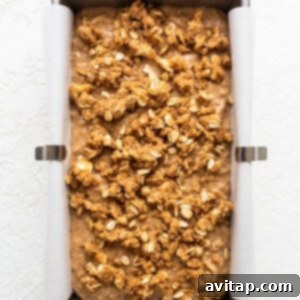 Apple bread batter in a loaf pan, topped with the prepared streusel, ready for baking.