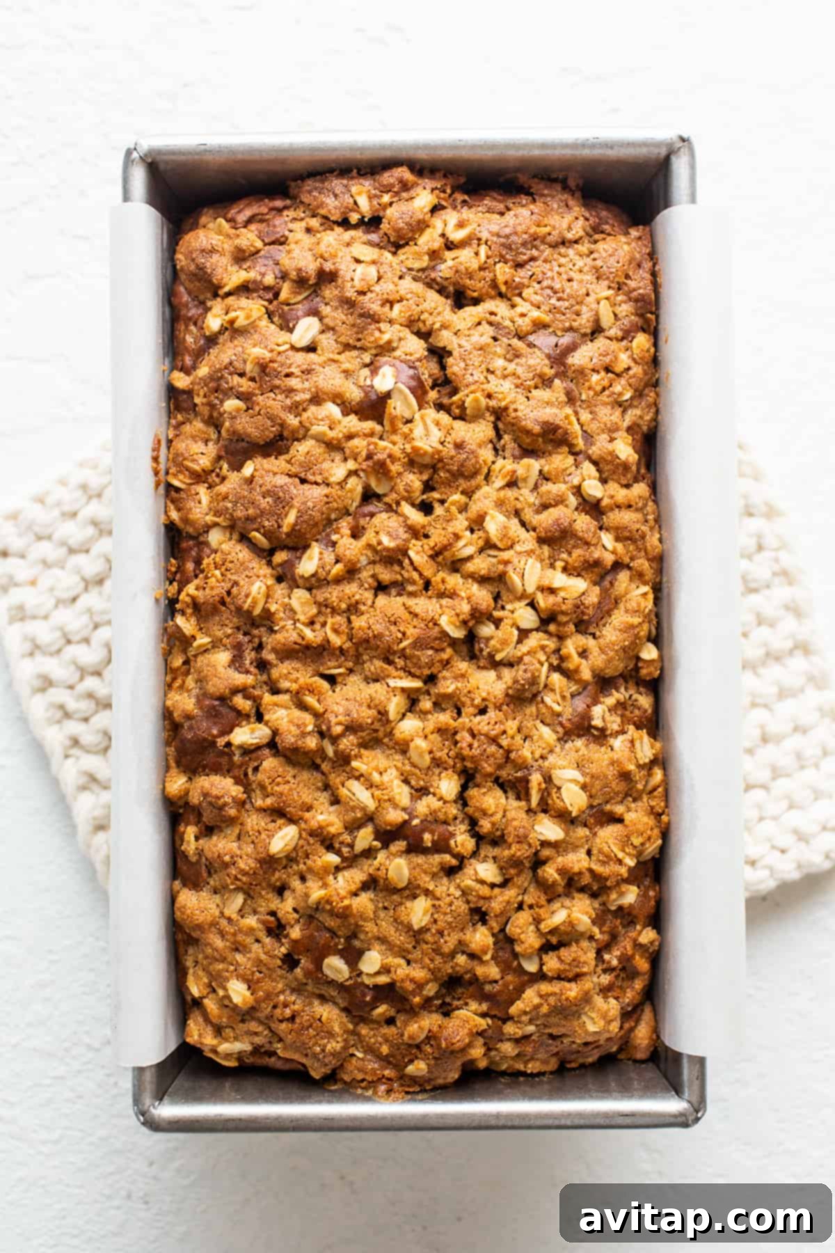 A single, perfectly sliced piece of Peanut Butter Apple Streusel Bread resting on a white plate.