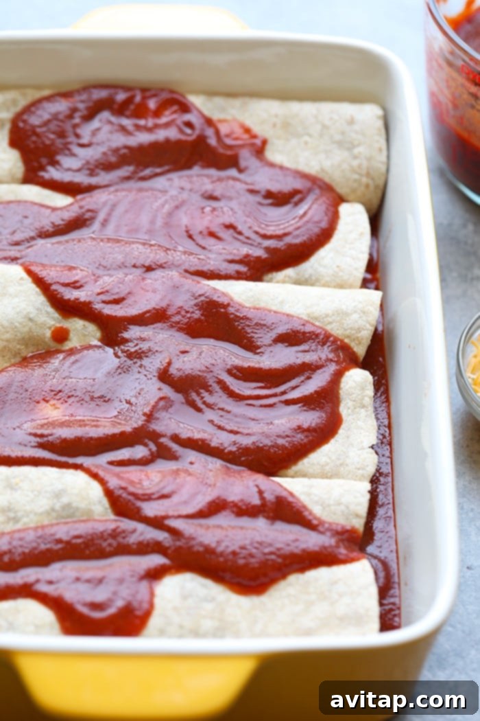 Healthy enchiladas covered with homemade enchilada sauce in a baking dish before baking