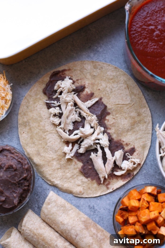 Black beans and shredded chicken being placed into an open tortilla for enchilada filling