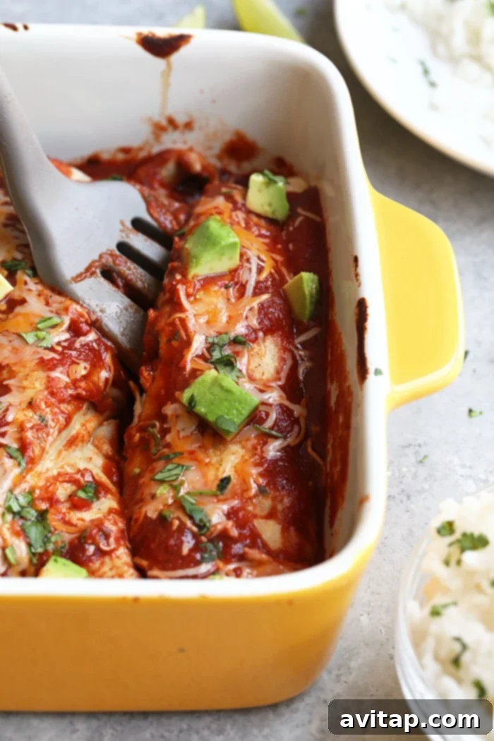Spatula dishing out a healthy enchilada from a yellow baking dish onto a plate