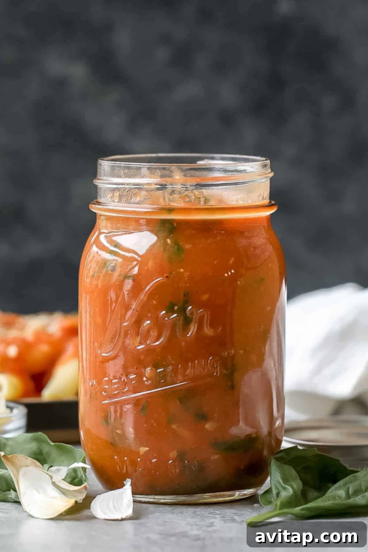 Make your own homemade tomato sauce using fresh, juicy tomatoes from the garden! Roast your tomatoes and puree them with garlic cloves, olive oil, and fresh basil. Jar of homemade roasted tomato sauce.