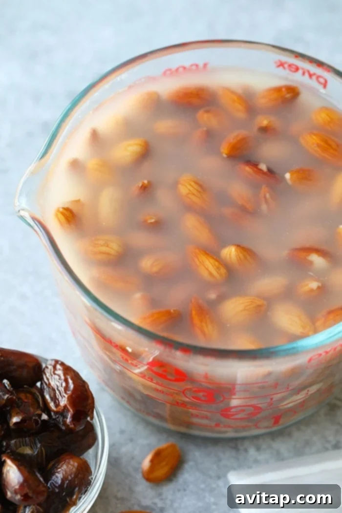 Raw almonds soaking in a bowl of water on a kitchen counter, preparing for almond milk production.