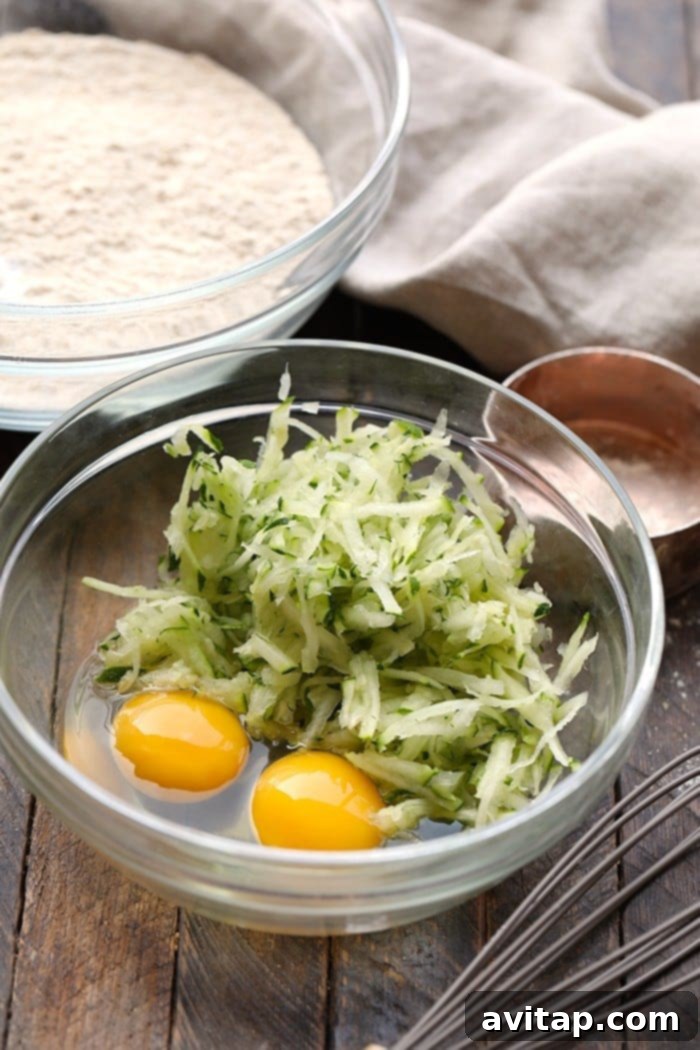 Close-up shot of fresh shredded zucchini and eggs, key ingredients for healthy zucchini waffles.