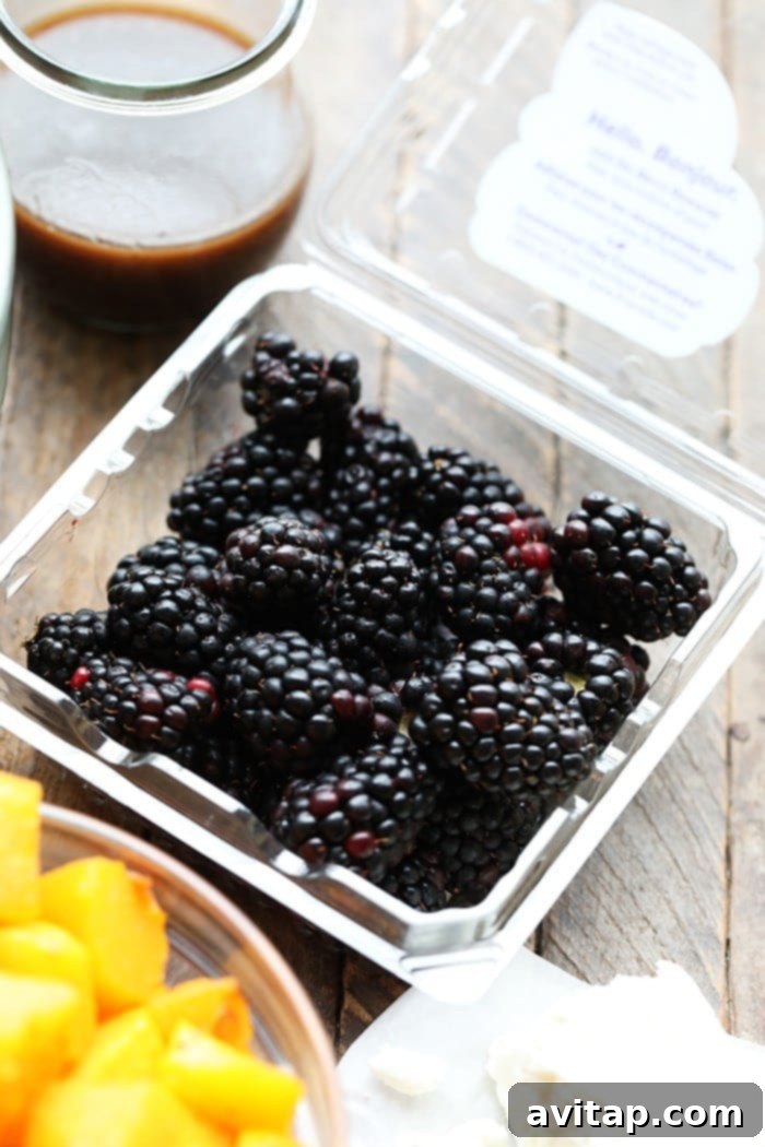 A carton of fresh, ripe Driscoll's blackberries, ready to be added to a delicious harvest salad.