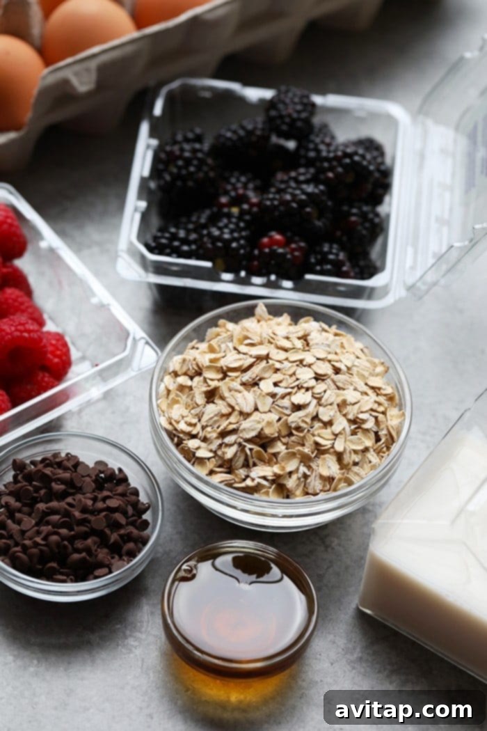 A vibrant selection of fresh ingredients for baked oatmeal including rolled oats, fresh berries, ripe banana, and dark chocolate chips