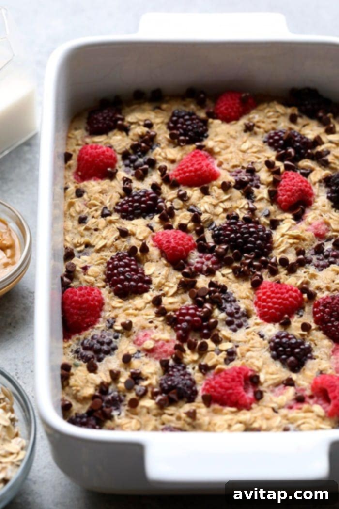 A large casserole dish of Dark Chocolate Berry Baked Oatmeal, freshly baked and glistening with melted chocolate and juicy berries