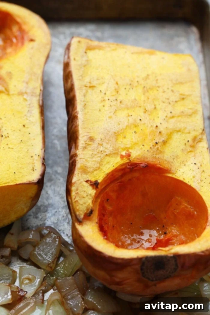 A baking sheet filled with roasted butternut squash, onions, jalapeños, and garlic cloves, fresh out of the oven.
