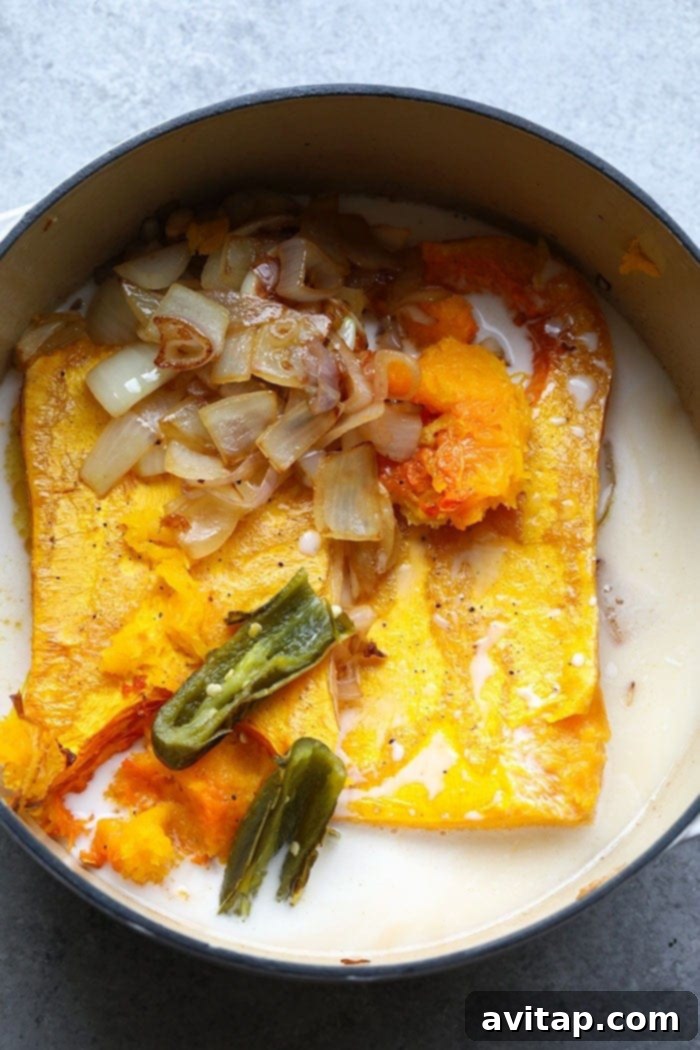 A pot of creamy orange butternut squash soup simmering on a stovetop, ready to be served.