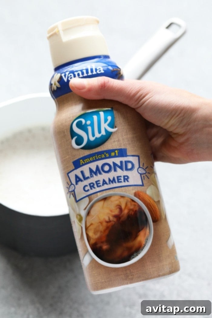 Ingredients for a maple pecan latte laid out on a wooden board, including Silk almond milk, creamer, cold brew, maple syrup, pecans, and cinnamon.