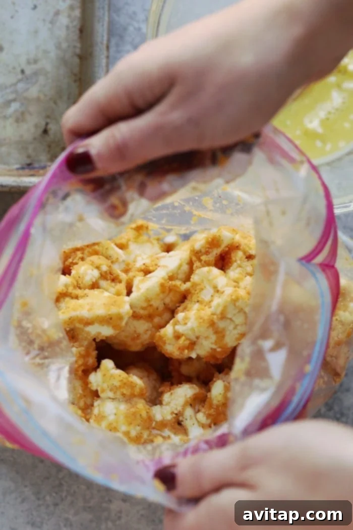 Cauliflower florets coated in spiced almond meal, ready for baking or air frying, shown in a plastic bag for easy tossing.