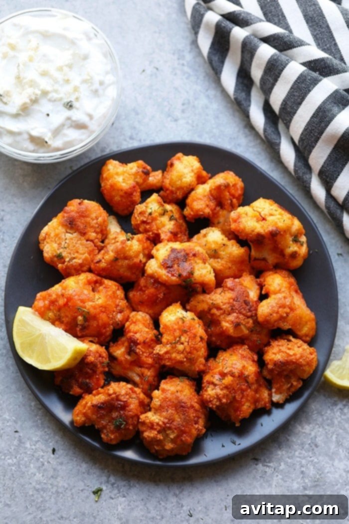 Platter of golden-brown buffalo cauliflower wings, freshly tossed in sauce and garnished with parsley, ready to be served.