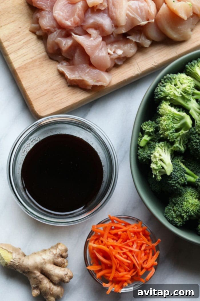 Individual bowls showcasing the fresh, vibrant ingredients for chicken stir fry: grated ginger, a bottle of soy sauce, crisp broccoli, shredded carrots, and raw chicken breast chunks.