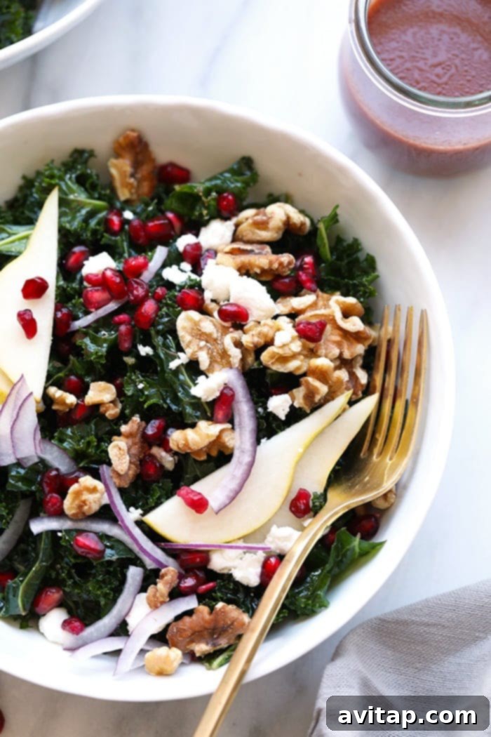 A large bowl filled with the colorful kale and pomegranate salad, ready to be served