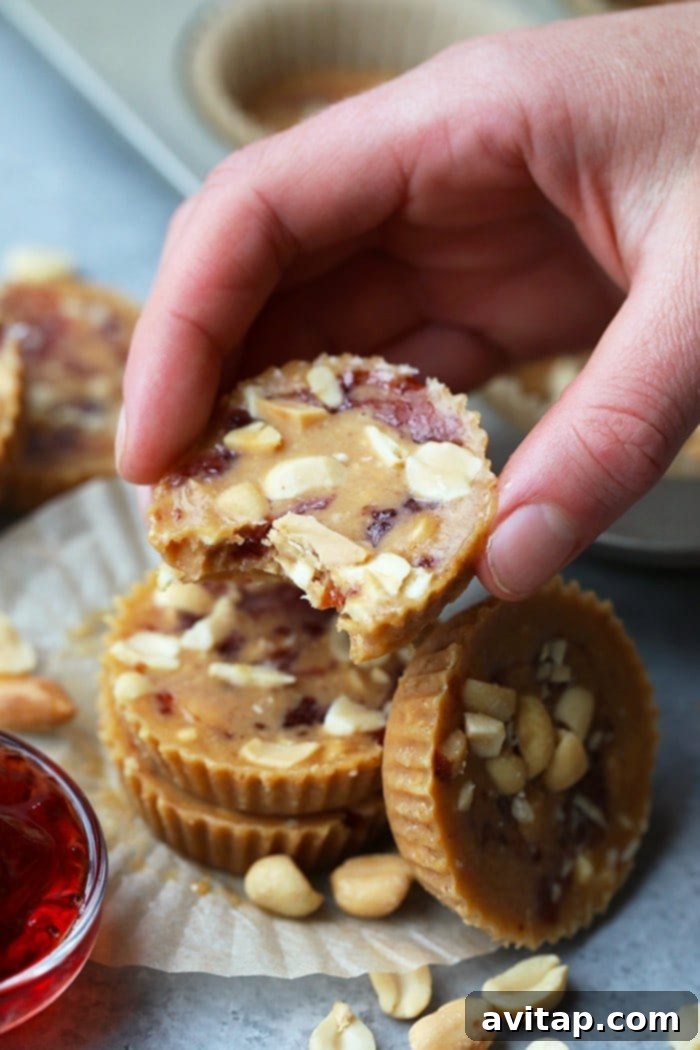 A hand gracefully holding a perfectly formed Crunchy Peanut Butter and Jelly Fat Bomb, highlighting the distinct layers and appealing texture, ready to be enjoyed.