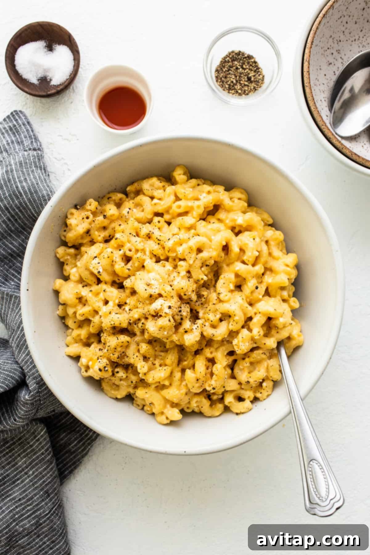 Made with 17g of protein and completely in your Instant Pot, this Protein Mac and Cheese is delicious, creamy, and easy to make! Creamy Instant Pot Protein Mac and Cheese served in a white bowl, garnished with fresh cracked pepper and a sprig of parsley.
