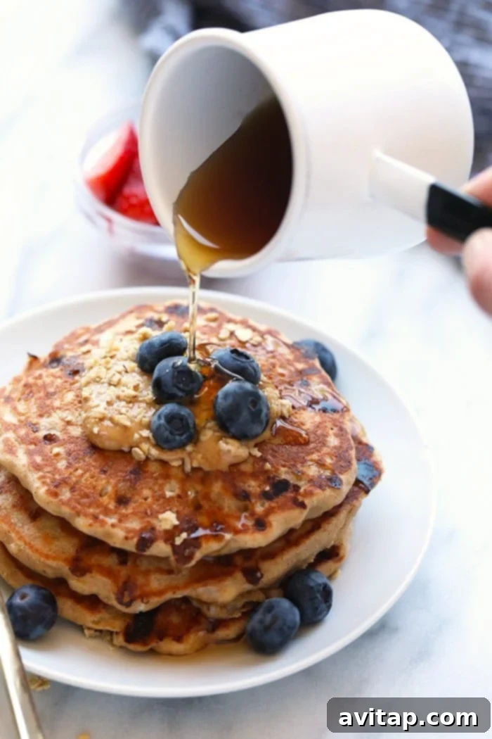 Cottage Cheese Protein Pancake for the win! Who's with me? If you're all about healthy pancakes and getting a protein boost at the same time then you will love this protein pancake recipe! It's made with 100% ground oat flour, cottage cheese, and mashed banana. Rich maple syrup being poured generously over a stack of golden-brown cottage cheese protein pancakes, ready to be enjoyed as a sweet and satisfying breakfast.