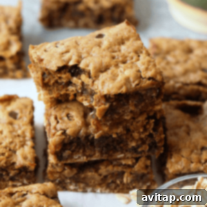 A stack of peanut butter cookie bars with a bowl of oats.