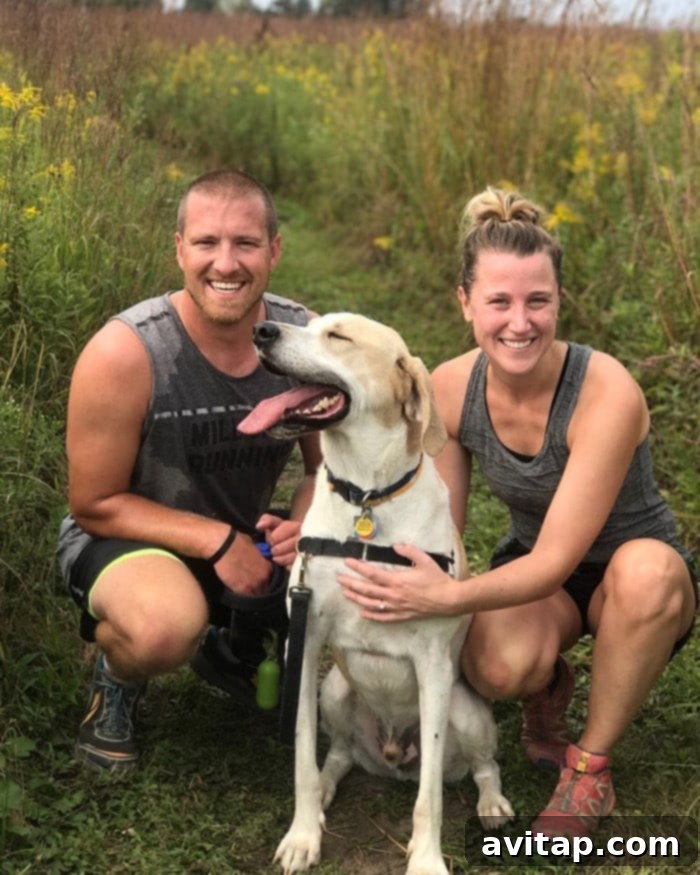Emily Richter and her husband Bryce, smiling with their large, friendly dog Thor in an outdoor setting.