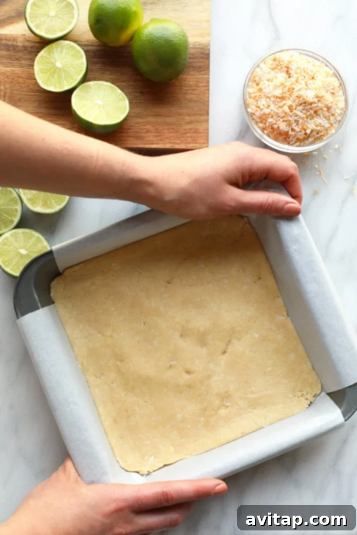 Healthy Key Lime Pie Bar Crust: Almond Flour & Coconut Foundation The golden-brown, baked almond flour and coconut crust of key lime pie bars, pressed into a baking pan.