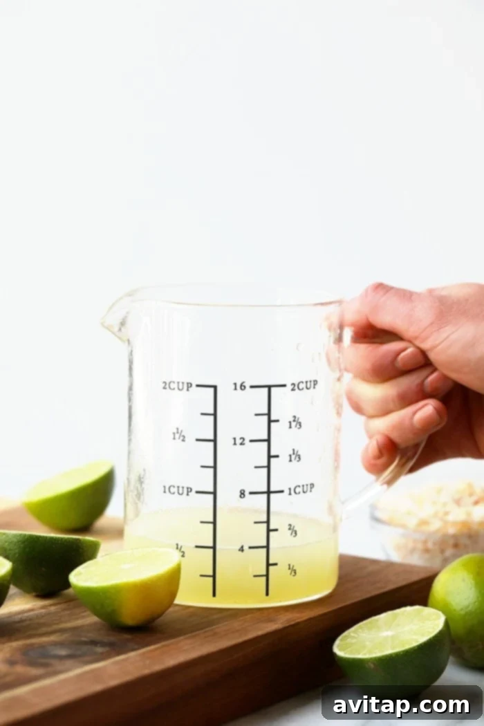 Fresh Key Lime Juice: The Zesty Heart of Healthy Key Lime Bars A measuring cup filled with freshly squeezed, vibrant key lime juice, showcasing the tart essence of the dessert.