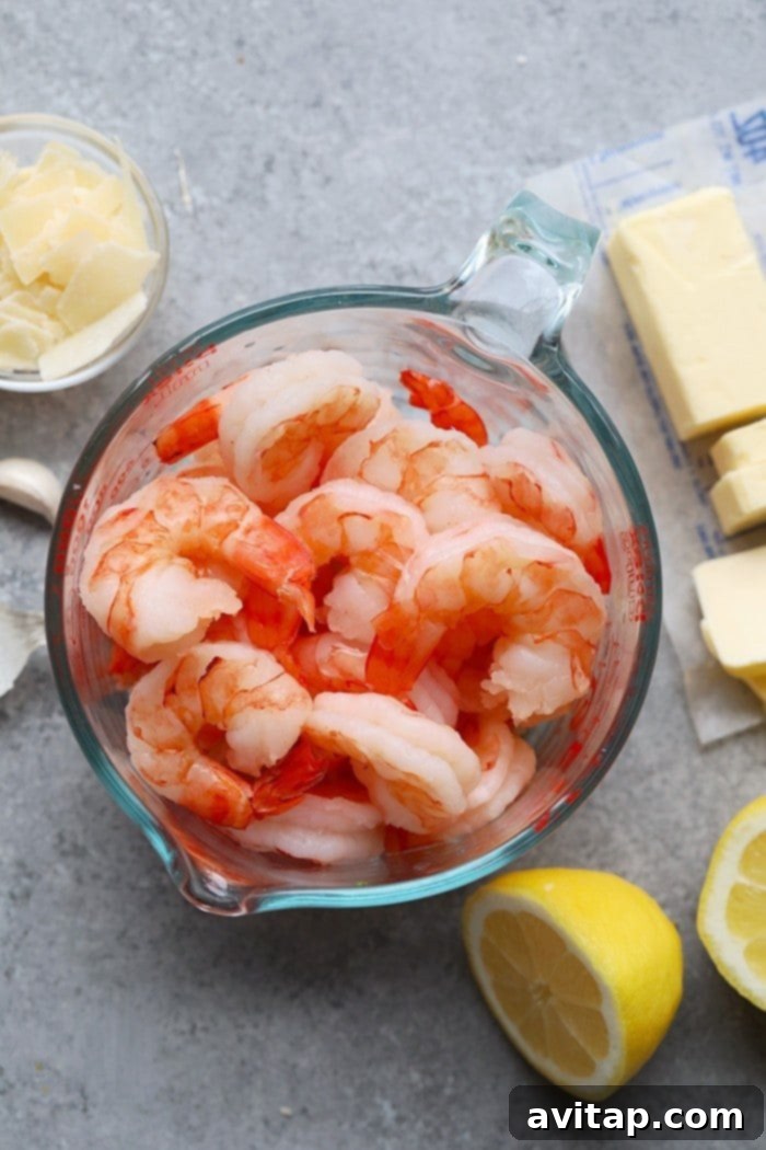 Close-up of a serving of shrimp scampi pasta with asparagus, tomatoes, and peas.