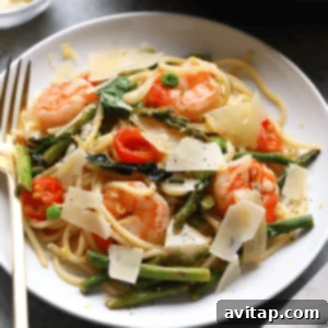 Shrimp scampi with asparagus served over a plate of pasta.