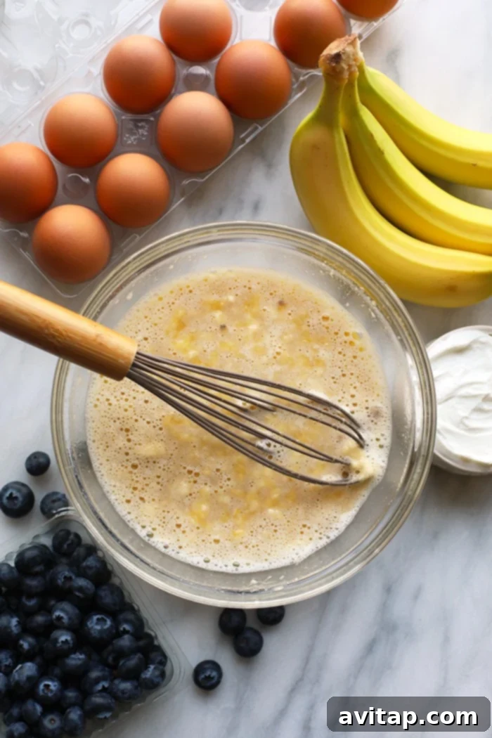 These healthy blueberry muffins are sweetened with honey and bananas and are moistened with greek yogurt! You can't go wrong with a blueberry muffin and a cup of coffee for breakfast! A mixing bowl with all wet ingredients