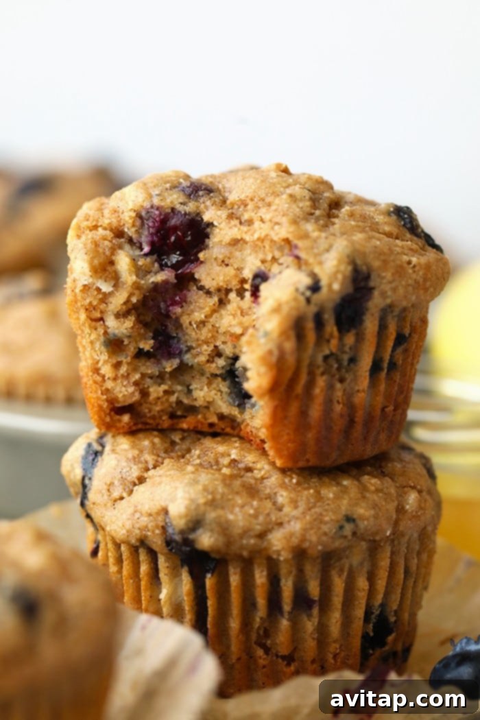 Everyone loves a classic blueberry muffin! These healthy blueberry muffins are packed with tart blueberries, honey, bananas, and greek yogurt! They are healthy and delicious! a blueberry muffin with a bite taken out