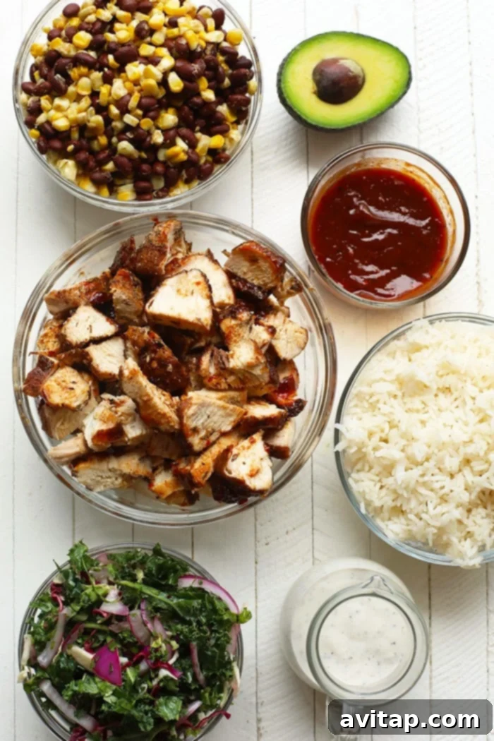 A collection of fresh ingredients laid out for making BBQ chicken bowls, including chicken, corn, black beans, kale, and various spices.