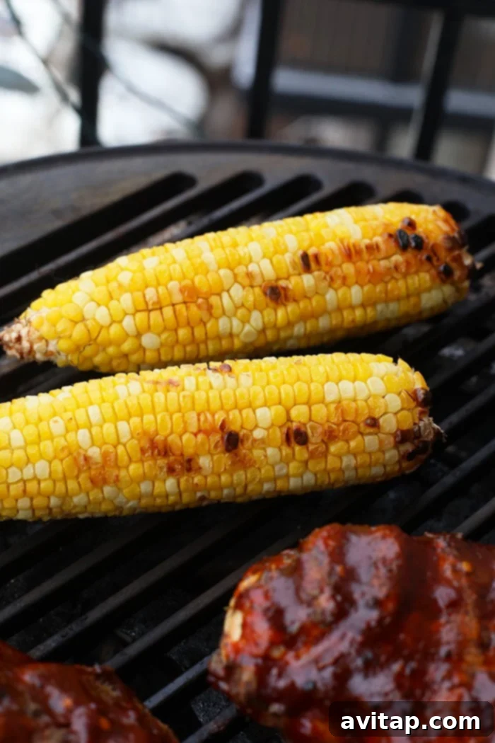 A close-up of BBQ chicken and corn sizzling on a grill, with beautiful grill marks.