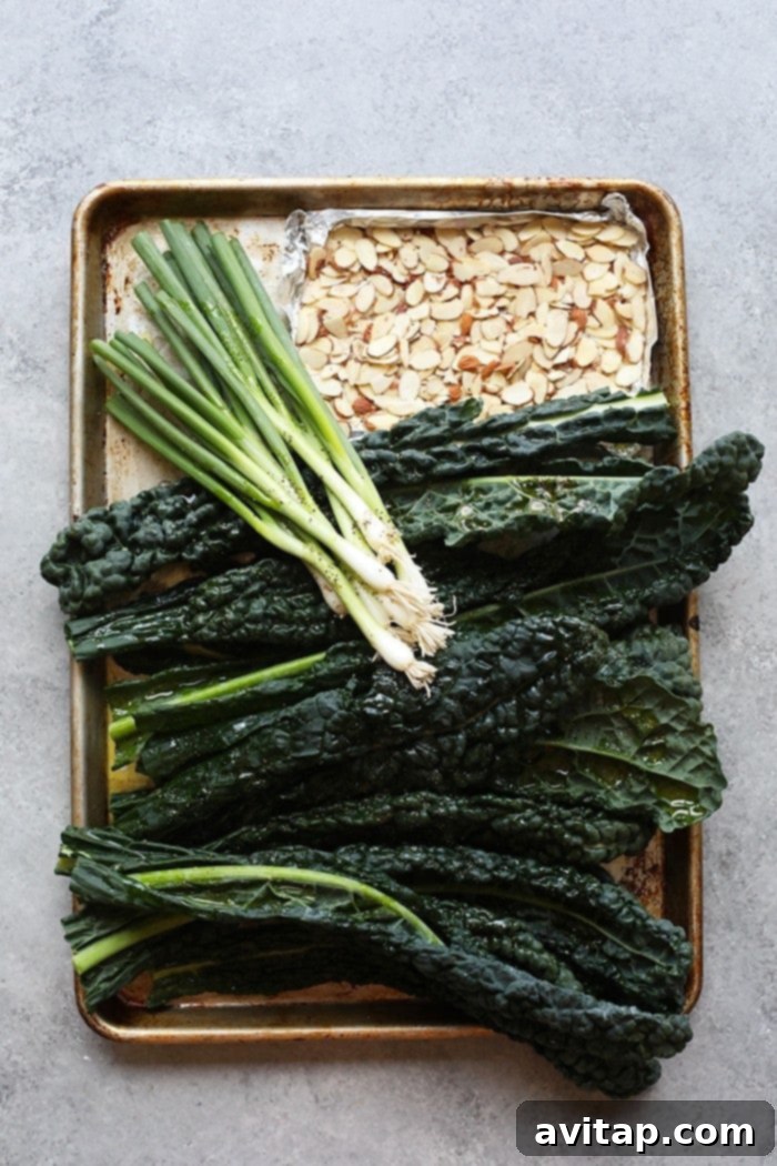 Close-up of kale, green onions, and almonds on a cookie sheet, ready for grilling.