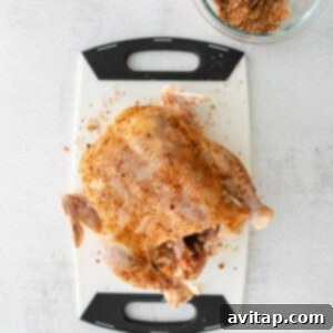 A Beer Can Chicken seasoned with spices, sitting on a cutting board.