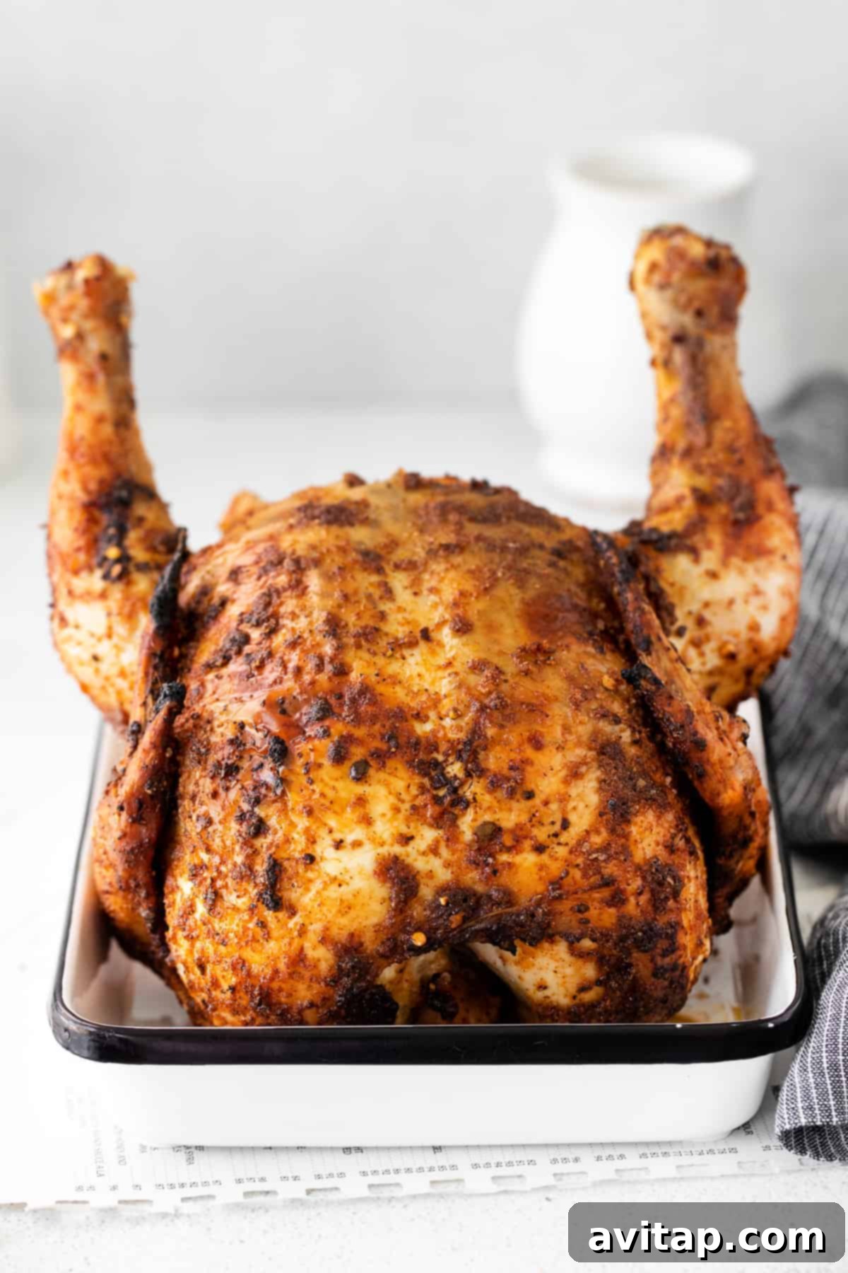 Juicy Beer Can Chicken: Ready for Carving A perfectly cooked beer can chicken, still upright on a can, resting in a white pan, ready to be carved.