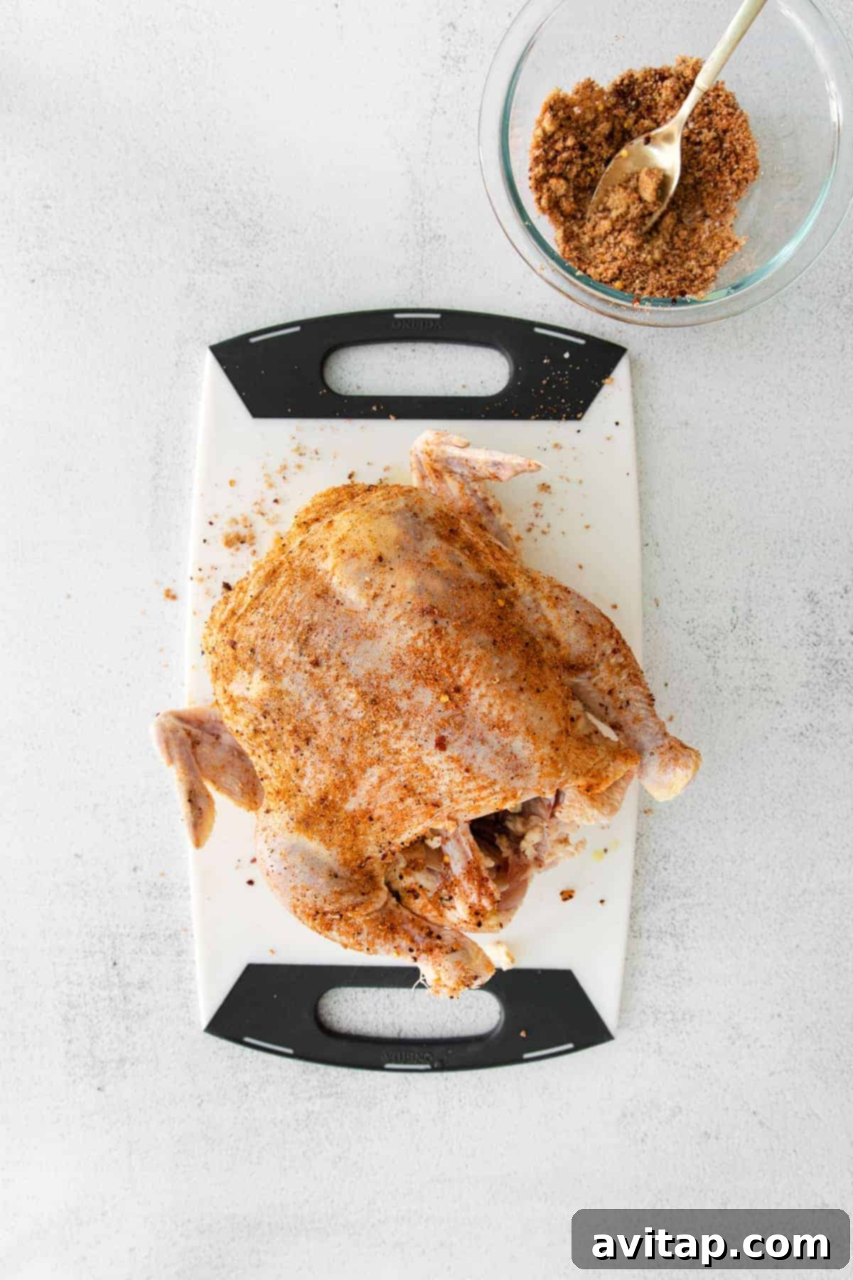 Seasoned Raw Chicken for Beer Can Recipe A raw whole chicken on a cutting board, expertly seasoned with a dry rub, ready for beer can cooking.